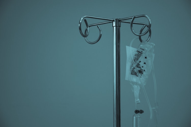 An empty IV hangs from a metal pole.
