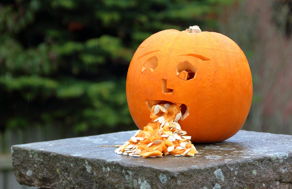 A pumpkin throwing up pumpkin seeds on a wall.