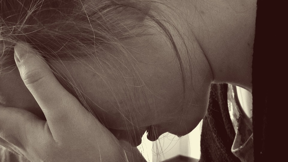 A sepia photo of a woman crying with her head in her hands.