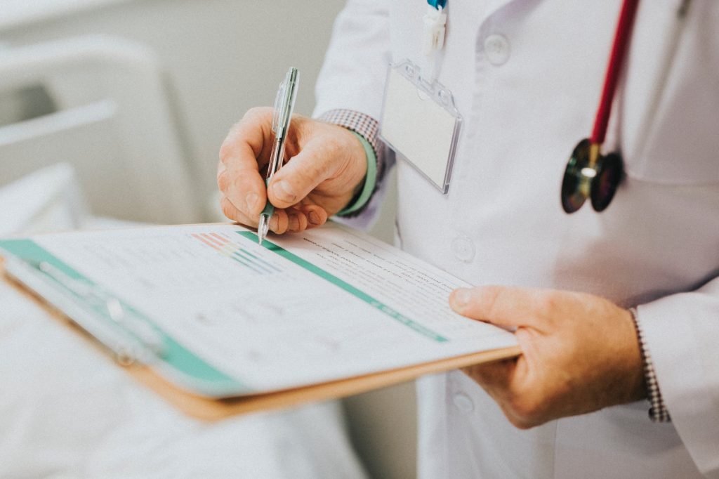 A doctor studies a clipboard and makes notes.