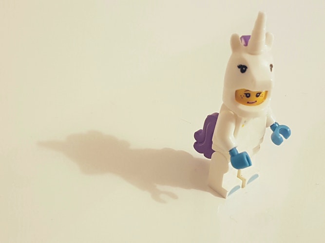 A photo of a lego person dressed as a white unicorn.