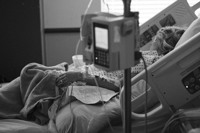 A black and white photo of a woman lying in a hospital bed.